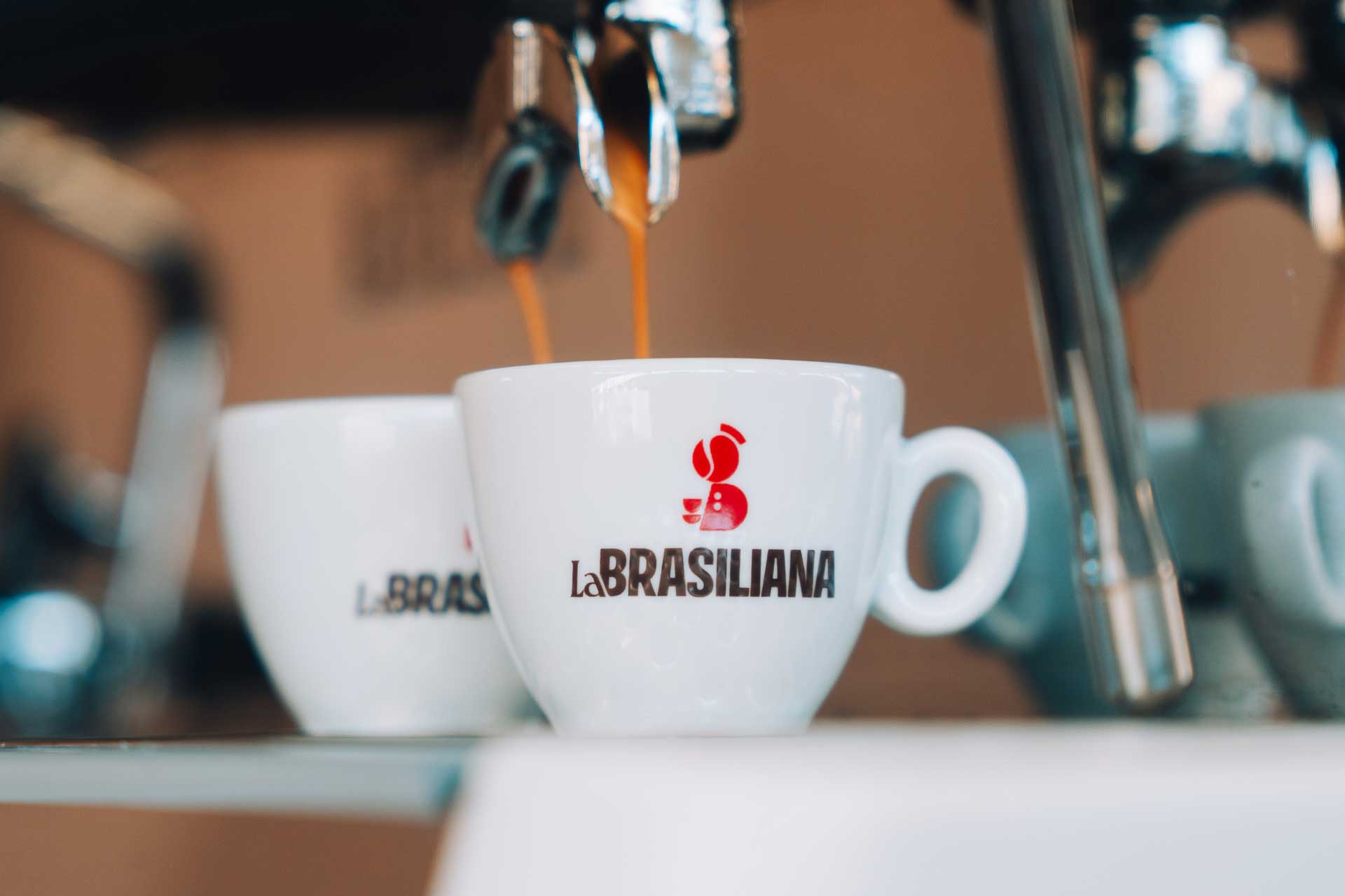 Tazzine LaBrasiliana sotto la macchina del caffé con espresso che scende.