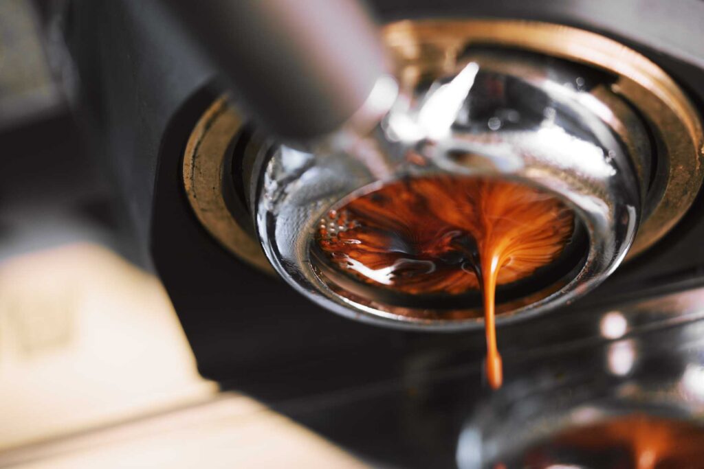 Espresso-Extraktion aus einer professionellen Kaffeemaschine, Detail der Crema und des Kaffeeflusses